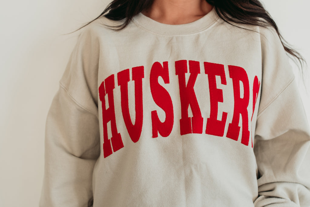 VARSITY RED HUSKERS - SAND CREWNECK